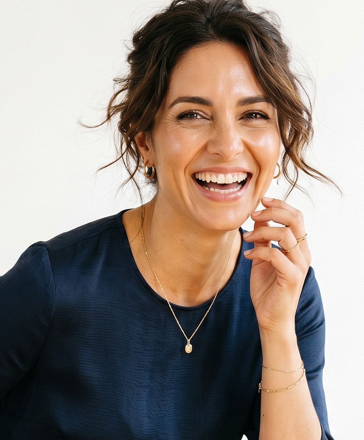 Woman smiling in elegant jewelry and navy shirt.