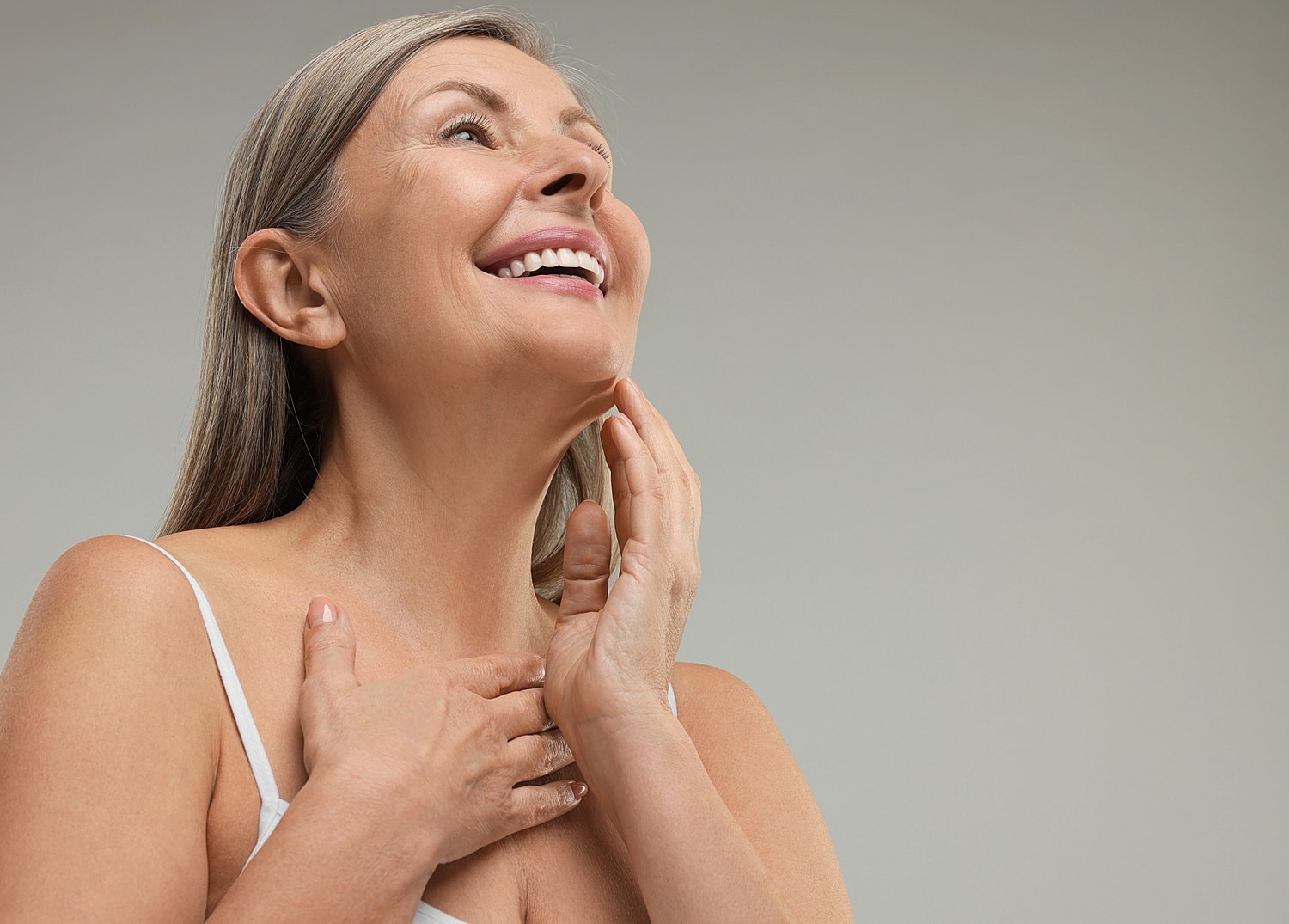 Smiling woman touching her face and neck.
