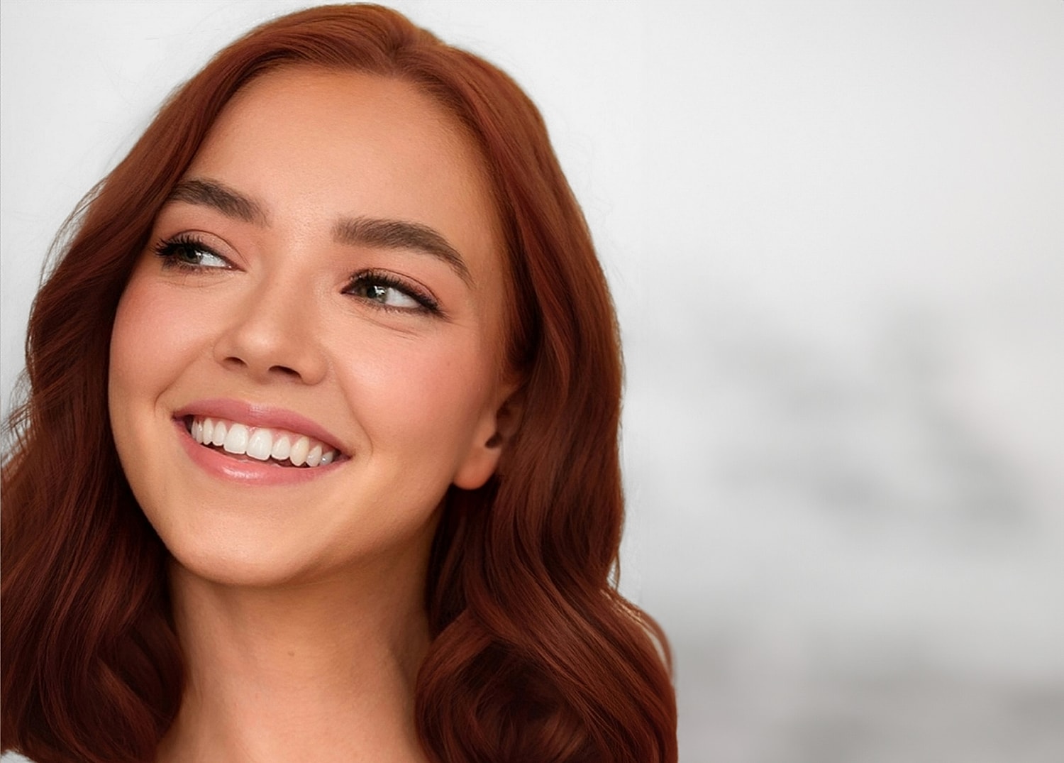 Smiling woman with wavy red hair.