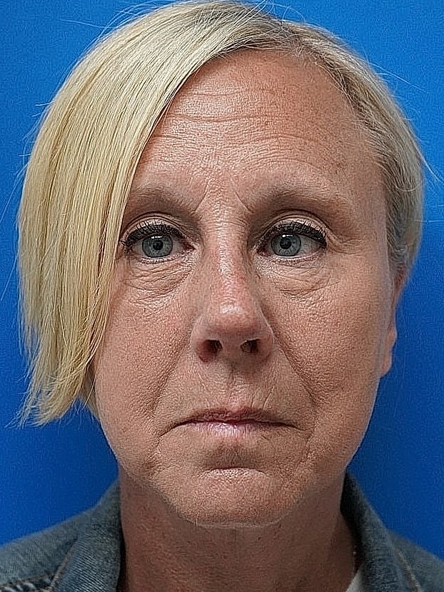 Woman with short blonde hair against blue background.