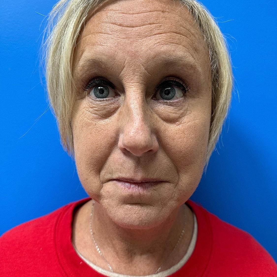 Woman with short blonde hair against blue background.