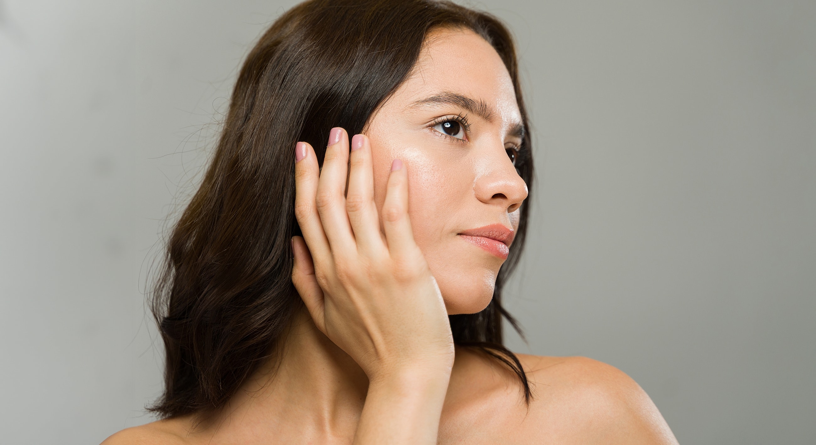 Woman with long hair touching her face.